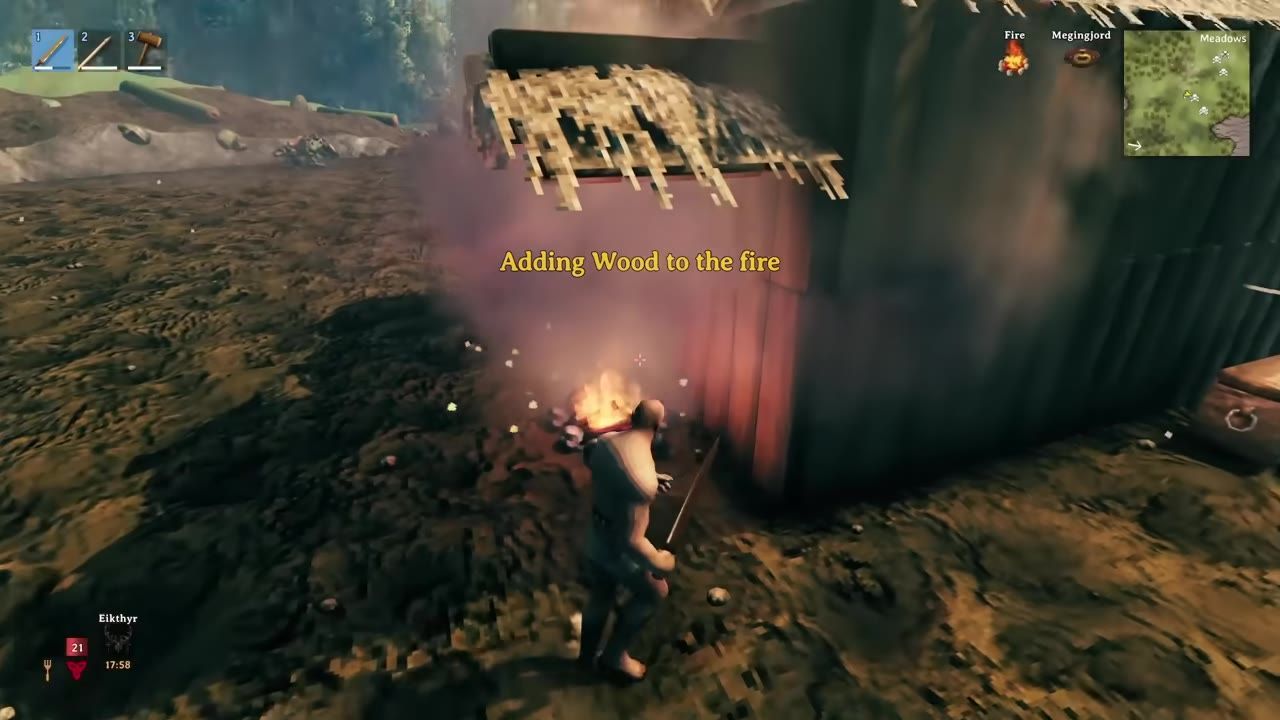 A character adds wood to a fire next to a sheltered hut.