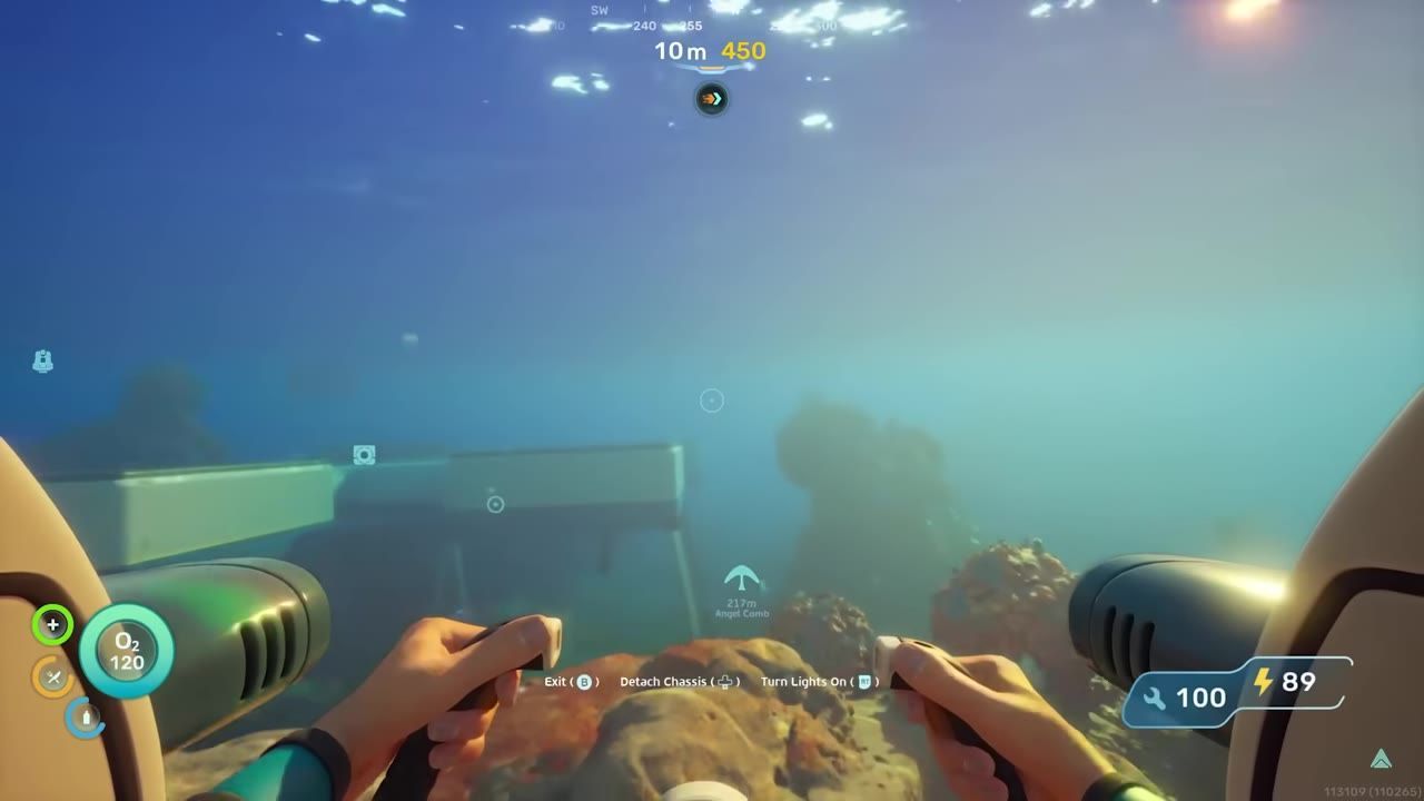 An underwater view showing hands operating controls, a visible structure, and surrounding aquatic environment.