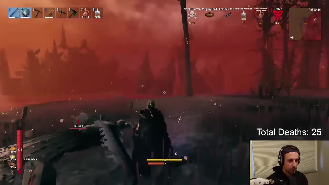 A Valheim combat scene in the Ashlands shows the player fighting a Vulture with HUD status effects, a minimap, and a small facecam overlay labeled Total Deaths: 25.