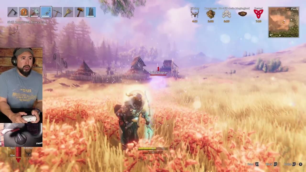 A character in a meadow facing a distant enemy Fuling Shaman while a webcam overlay shows a person playing.
