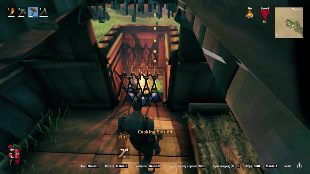 A character standing near a cooking station set over a fire inside a shelter.